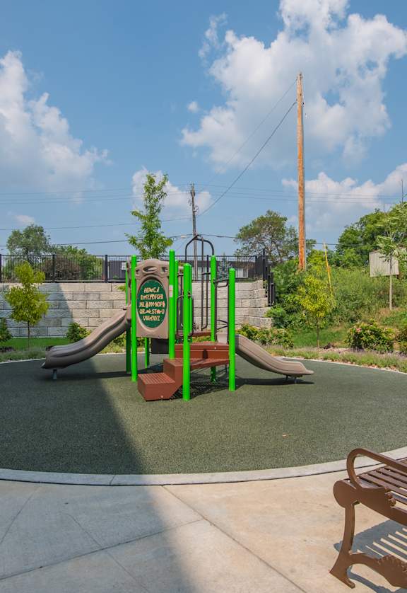 A playground with a green slide and a brown bench.