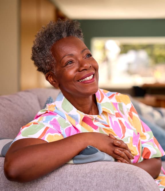 an older woman sitting on a couch smiling