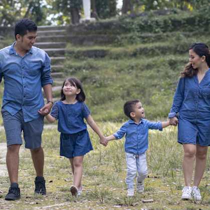 a family of four walks through a grassy field