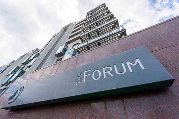 a sign for the forum in front of a tall building