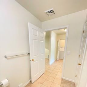 A white toilet is in a small bathroom with a white door.