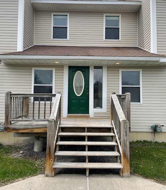A house with a green door and a wooden staircase leading to it.