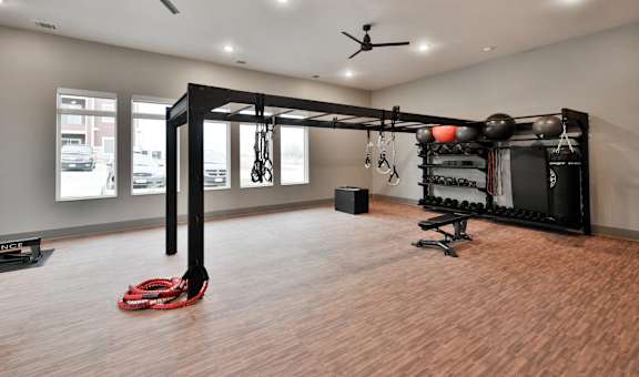 A gym room with a weight rack and a red kettlebell on the floor.
