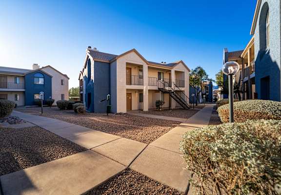 A sunny day in a residential area with apartment buildings and a sidewalk.