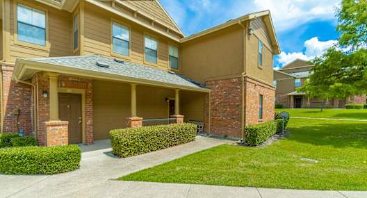 the front of an apartment building with a sidewalk and grass
