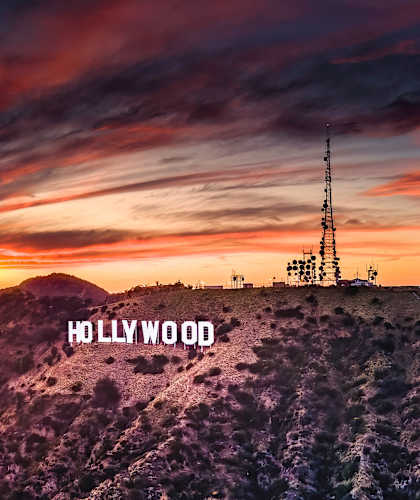 The Hollywood sign is displayed on a hilltop against a backdrop of a sunset.