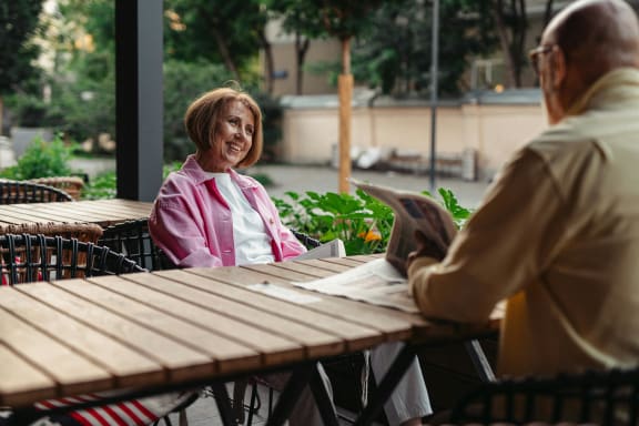 a man and woman sitting at a table reading a newspaper