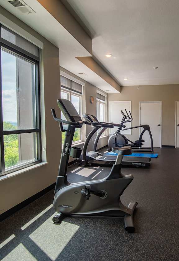 a gym with treadmills and other exercise equipment in a building with large windows
