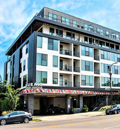 a large apartment building on a city street with cars parked in front of it
