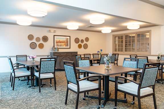 A dining room with a table surrounded by chairs.