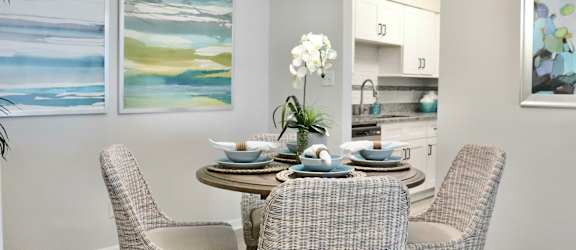 A dining room with a table set for four and two chairs.
