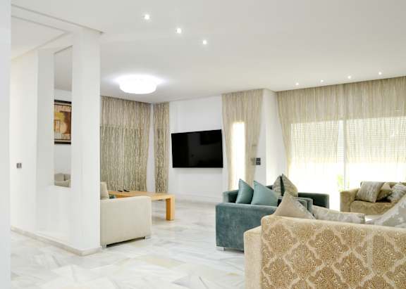 A living room with a white couch and a television on the wall.