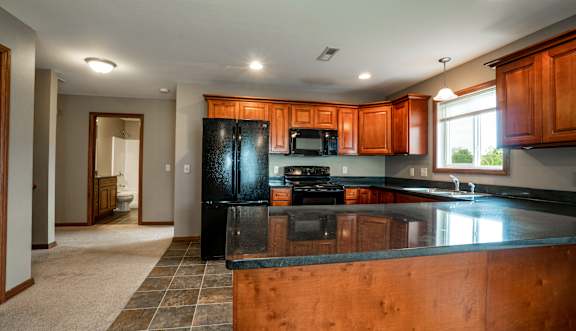 A kitchen with wooden cabinets and a black refrigerator.
