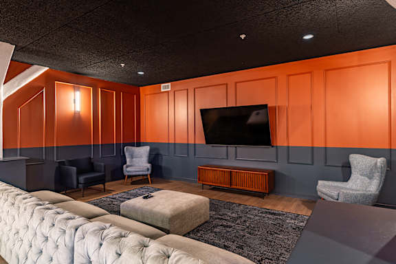 A living room with a grey couch and a television on the wall.