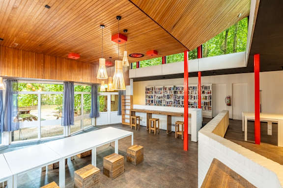 A room with a white table and chairs with a bookshelf in the background.
