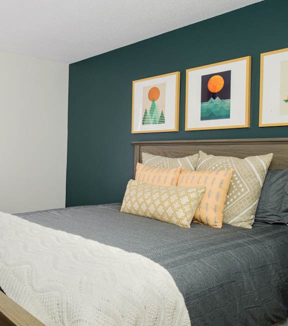 a bed with pillows in a room with a green wall