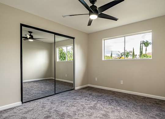 A room with a ceiling fan and a large mirror on the wall.