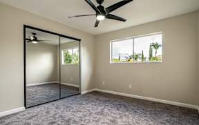 A room with a ceiling fan and a large mirror on the wall.