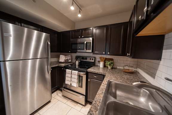 A modern kitchen with a stainless steel refrigerator and a granite countertop.