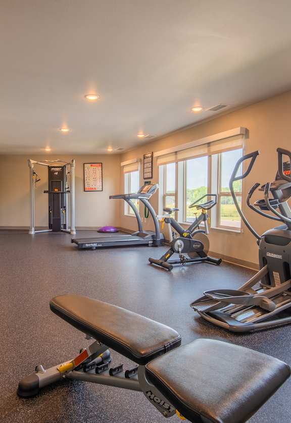 A gym with a variety of equipment including treadmills, weights, and exercise machines.