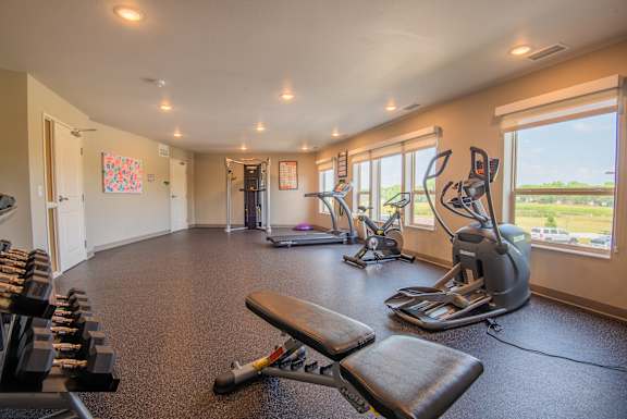 A gym with a variety of equipment including treadmills, weights, and exercise machines.