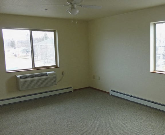 Image of a bedroom with AC, base heaters, and windows