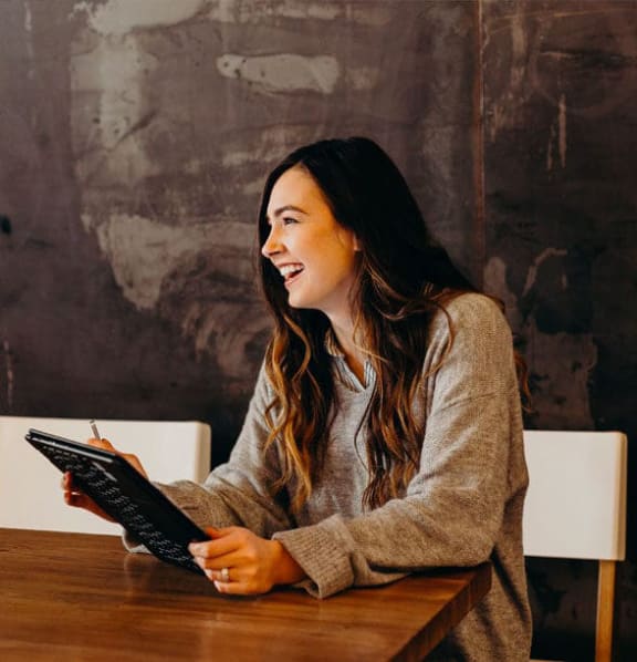 a woman sitting at a table with a tablet