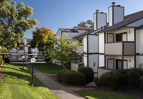 A white building with a black roof and a sign on the lawn.