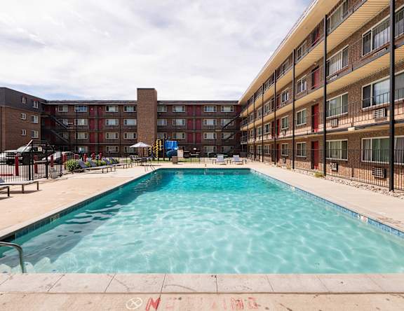 the pool is in front of a red brick building with a swimming pool