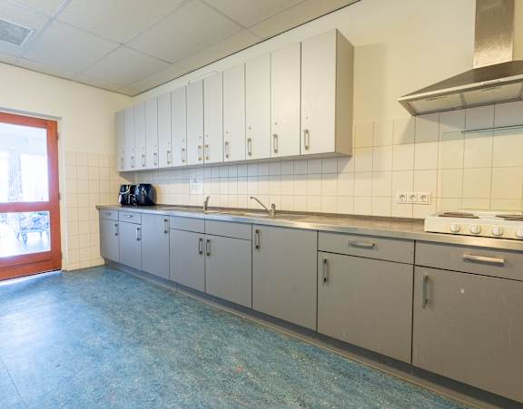 A kitchen with a stove, cabinets, and a window.