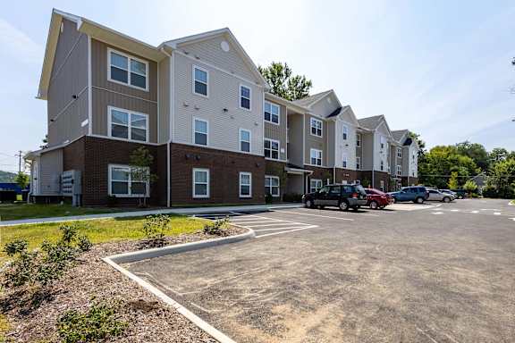 A parking lot in front of a multi-story apartment building.