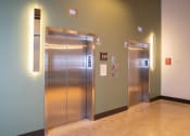 Thumbnail 11 of 23 - two stainless steel elevators in a hallway in a building