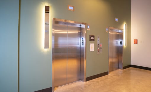 two stainless steel elevators in a hallway in a building