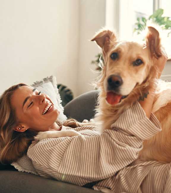 A woman is sitting on a couch with a dog on her lap.