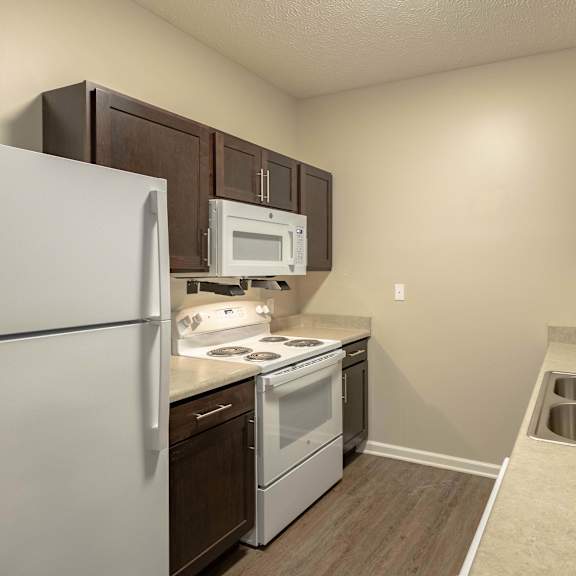 A kitchen with a white refrigerator, white stove, and white microwave.