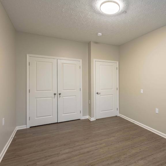 A room with two white doors and wooden flooring.