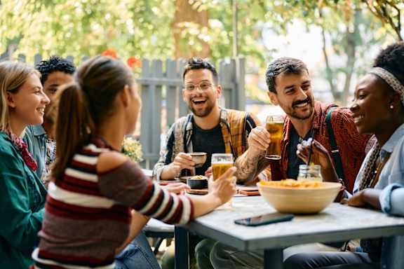 A group of people are sitting around a table enjoying food and drinks. at Textile Apartments, Cincinnati, OH, 21286
