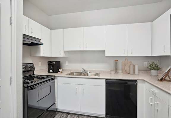an empty kitchen with white cabinets and black appliances