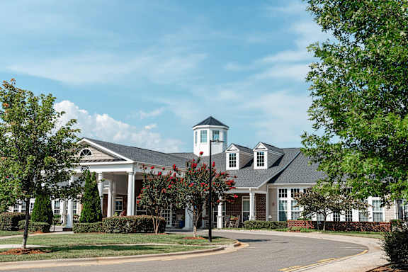 A white building with a black roof and a tower with a black roof.