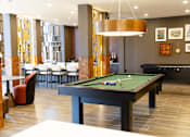 Thumbnail 2 of 9 - A billiard table is in the middle of a room with a bar and chairs. at District on the Etowah Apartments, Canton Georgia