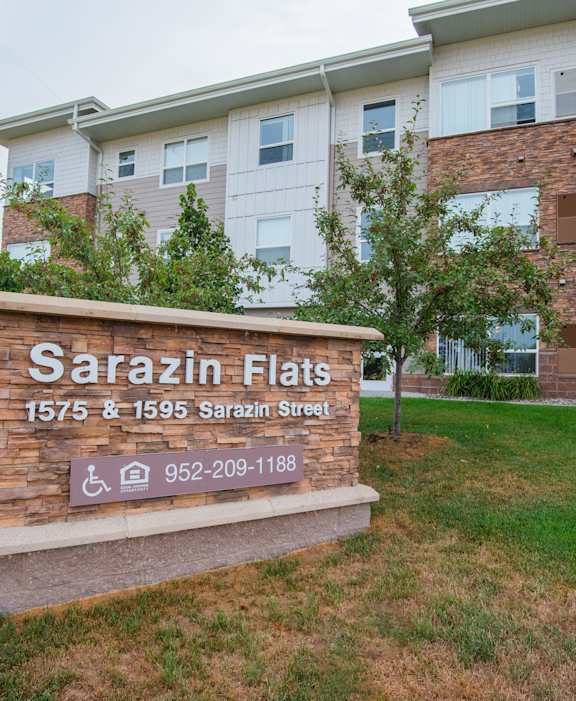 A sign for Sarazin Flats in front of a building.