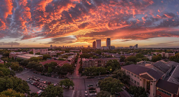 A cityscape with buildings and a parking lot under a vibrant sky.
