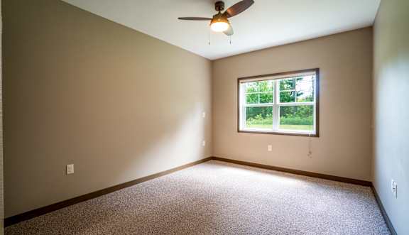 A room with a ceiling fan and a window.