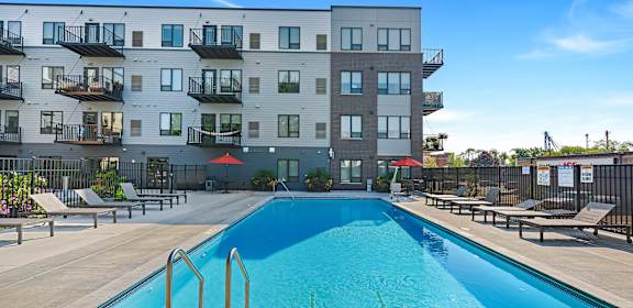 A large swimming pool in front of a multi-story apartment building.
