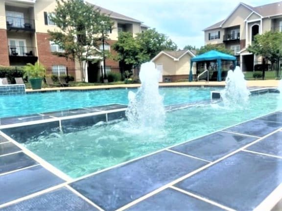 a swimming pool with water fountains in front of a building
