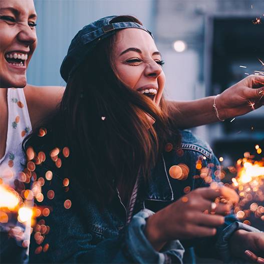 Two women laughing and holding sparklers.