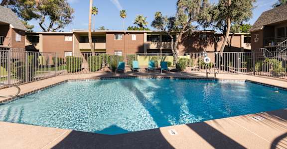 a swimming pool with chairs in front of a building