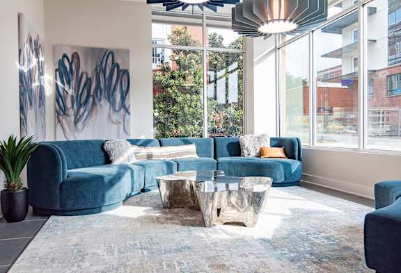 A blue couch with a white pillow is in the middle of a room with a large painting on the wall.