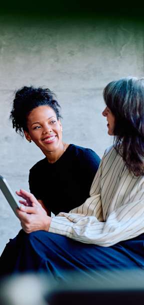 Two people sitting and looking at a tablet.