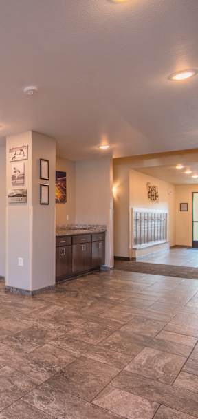 A living room with a stone floor and a white wall with pictures and a lamp.